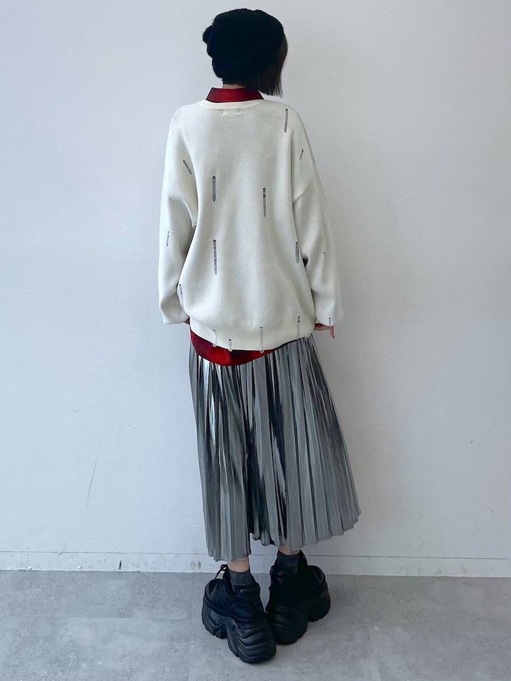 ブラック系のスニーカー、グレー系のスカート、ホワイト系のニット/セーターを着用したレディースの秋コーディネートの6枚目の写真