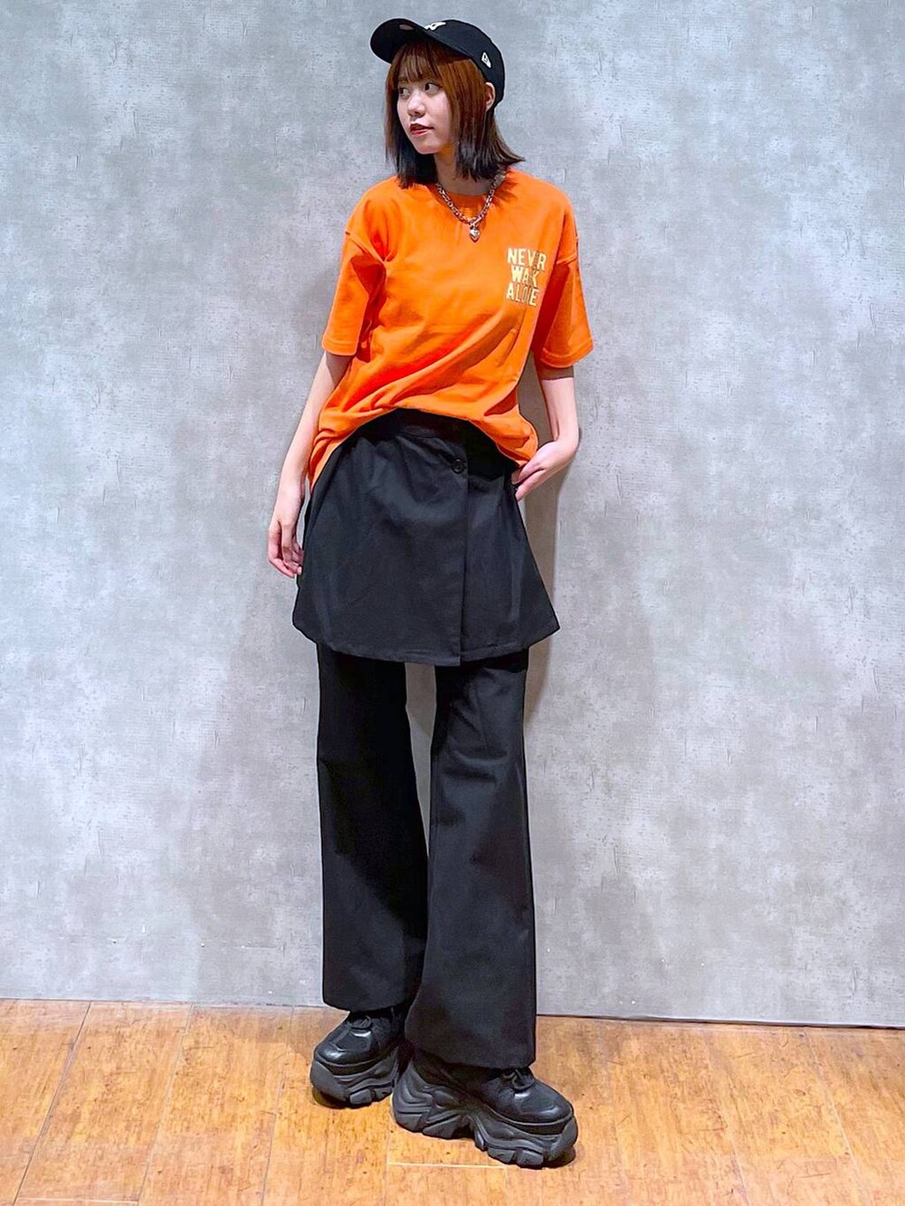 ブラック系のスニーカー、オレンジ系のTシャツ/カットソー、ブラック系のチノパンツを着用したレディースの夏コーディネートの7枚目の写真