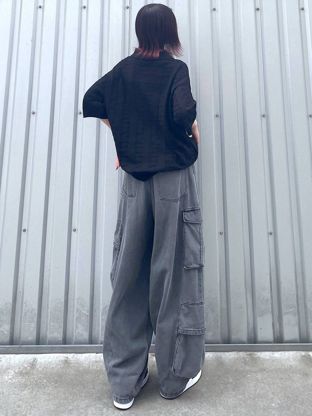 ブラック系のニット/セーター、ブラック系のデニムパンツ、ブラック系のベルトを着用したレディースの春コーディネートの2枚目の写真