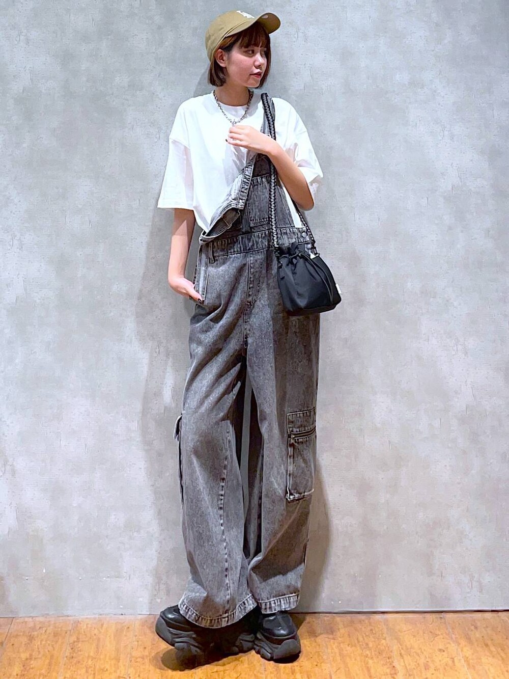 ブラック系のスニーカー、ブラック系のショルダーバッグ、ホワイト系のTシャツ/カットソーを着用したレディースの夏コーディネートの2枚目の写真