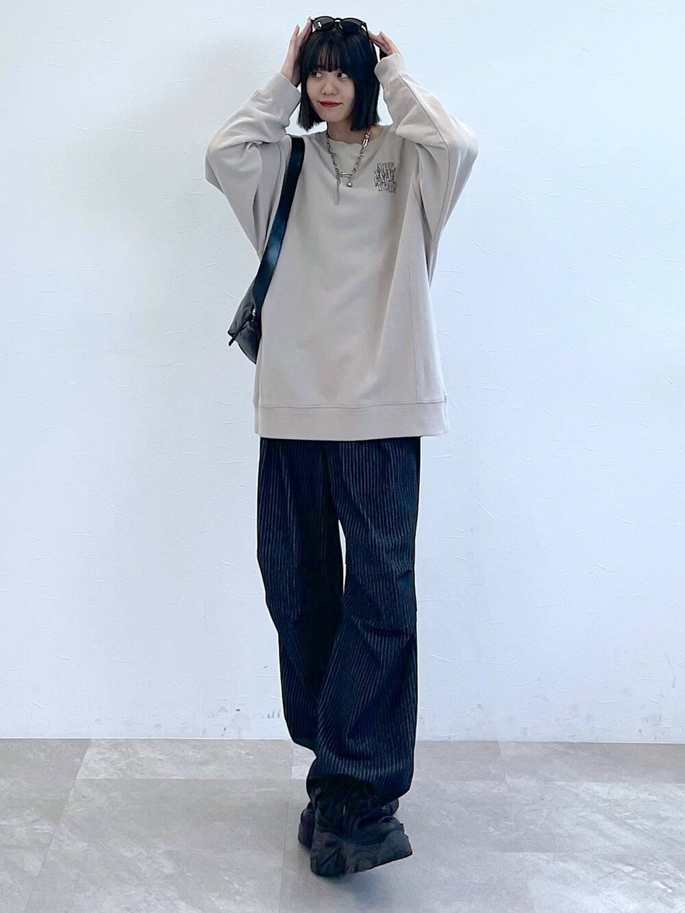 ブラック系のスニーカー、ブラック系のショルダーバッグ、ブラック系のデニムパンツを着用したレディースの秋コーディネートの2枚目の写真