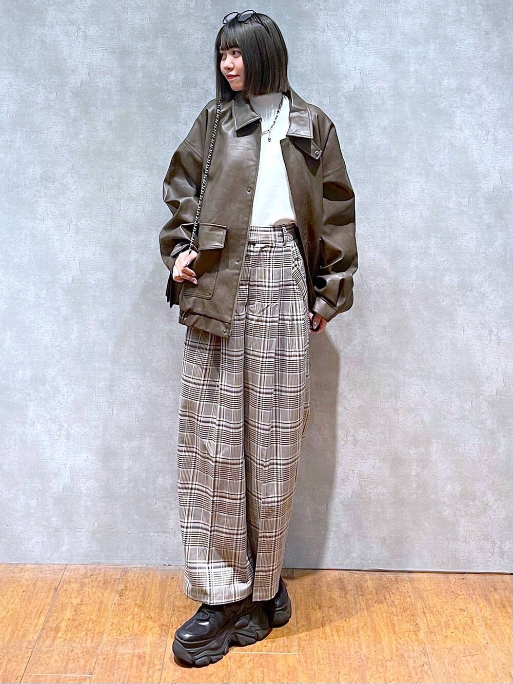 ブラック系のスニーカー、ホワイト系のニット/セーター、ベージュ系のスラックスを着用したレディースの秋コーディネートの2枚目の写真