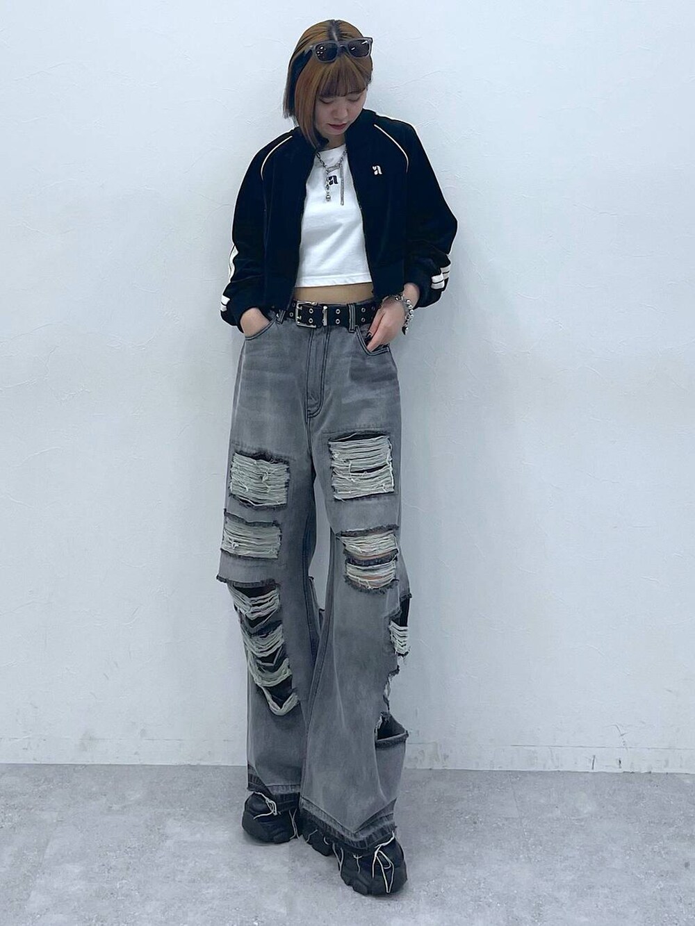 ブラック系のデニムパンツ、ブラック系のスニーカー、ホワイト系のTシャツ/カットソーを着用したレディースの夏コーディネートの3枚目の写真