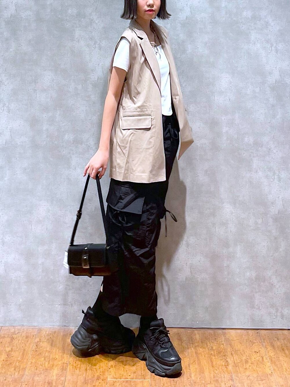 ブラック系のスニーカー、ブラック系のハンドバッグ、ホワイト系のTシャツ/カットソーを着用したレディースの夏コーディネートの2枚目の写真