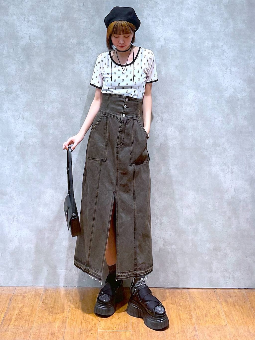 ブラック系のスニーカー、ブラック系のデニムスカート、ブラック系のハンドバッグを着用したレディースの夏コーディネートの2枚目の写真