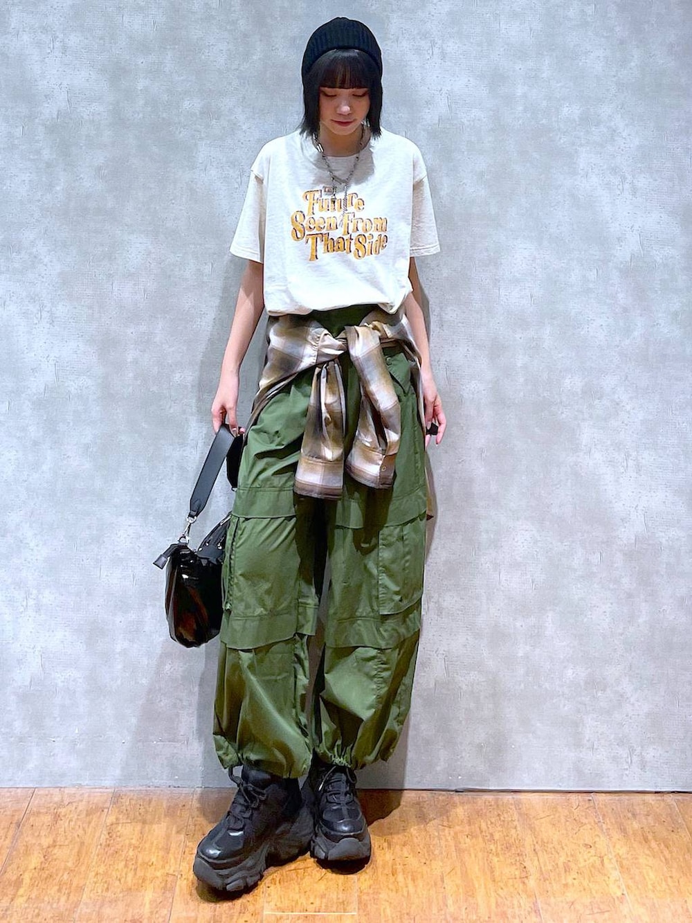 ブラック系のスニーカー、グリーン系のその他パンツ、ベージュ系のTシャツ/カットソーを着用したレディースの夏コーディネートの2枚目の写真