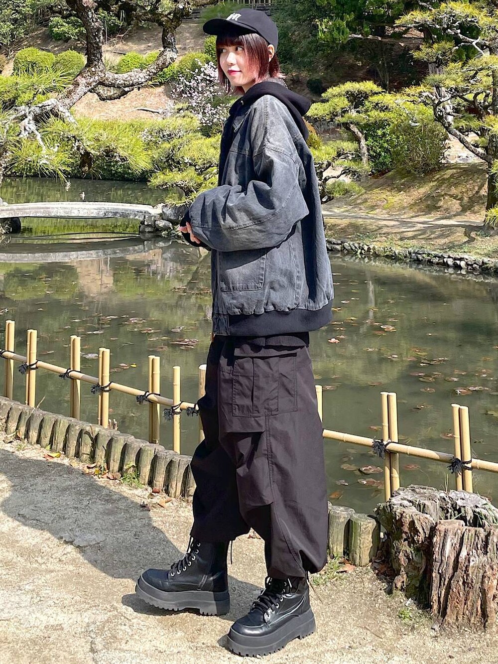 ブラック系のデニムジャケット、ブラック系のブーツ、ブラック系のスラックスを着用したレディースの春コーディネートの2枚目の写真