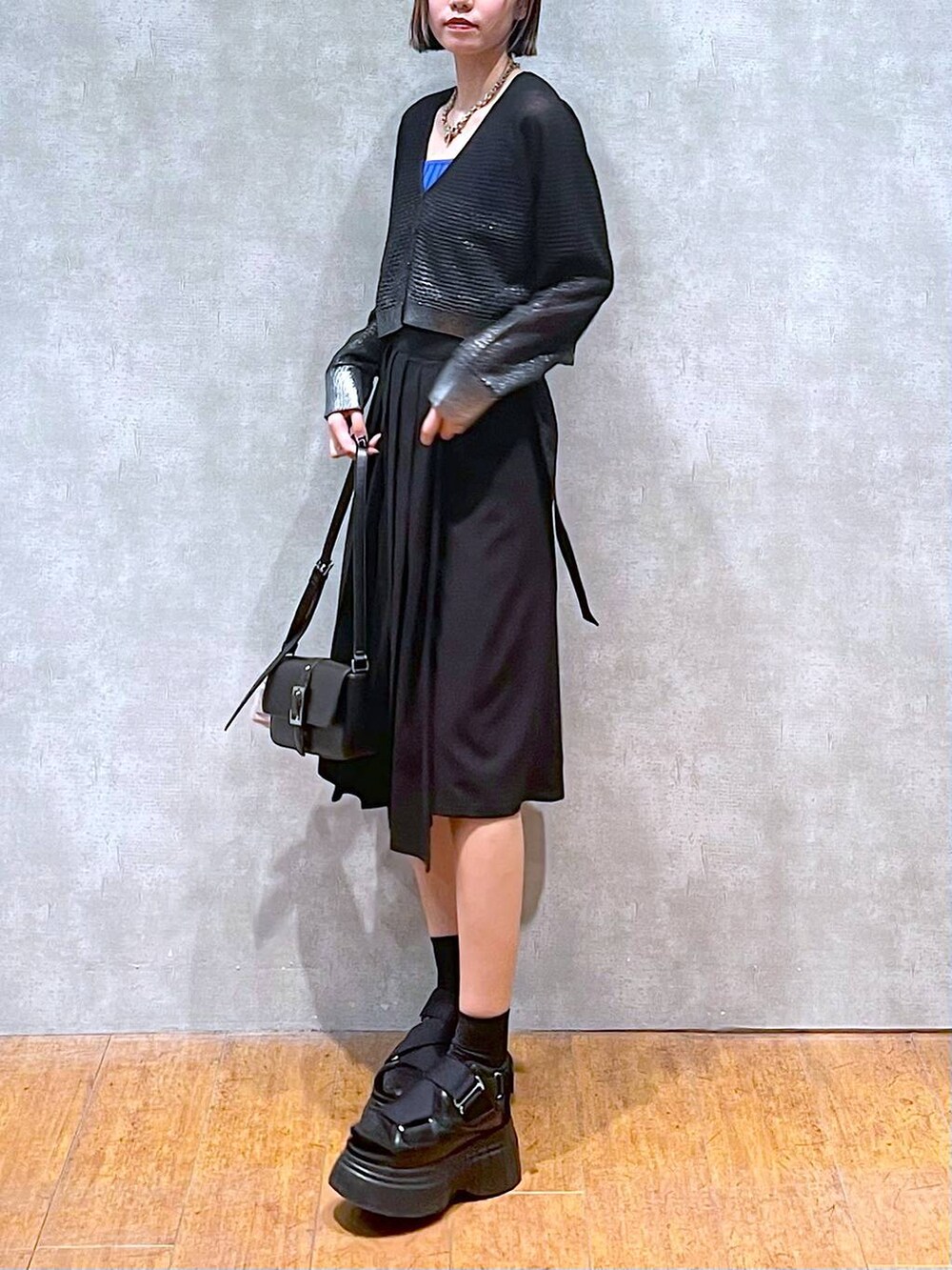 ブラック系のスニーカー、ブルー系のタンクトップ、ブラック系のスカートを着用したレディースの夏コーディネートの6枚目の写真