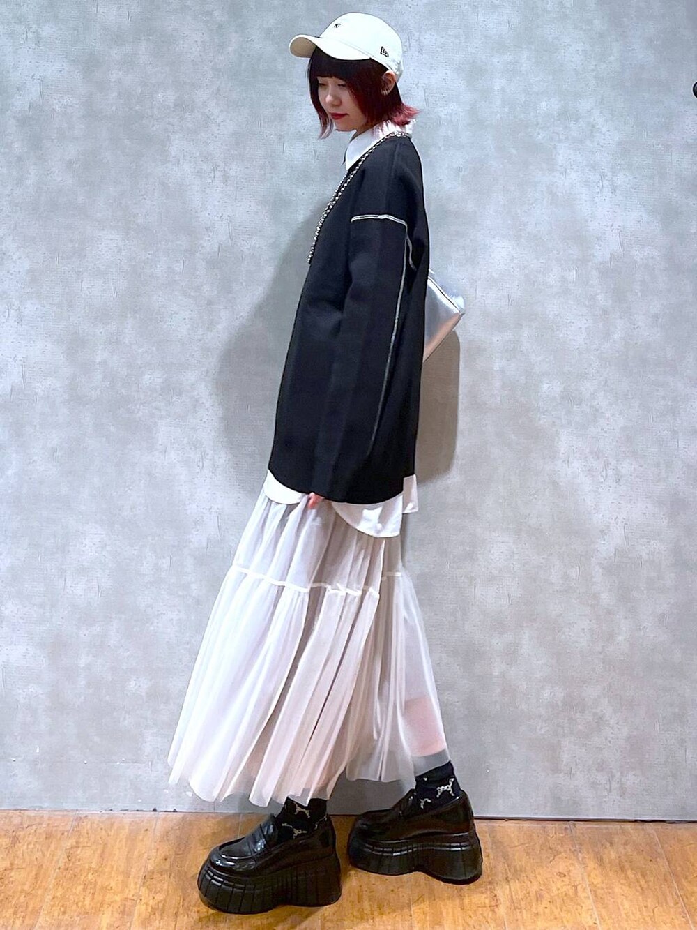 シルバー系のショルダーバッグ、ホワイト系のシャツ/ブラウス、ブラック系のニット/セーターを着用したレディースの春コーディネートの6枚目の写真