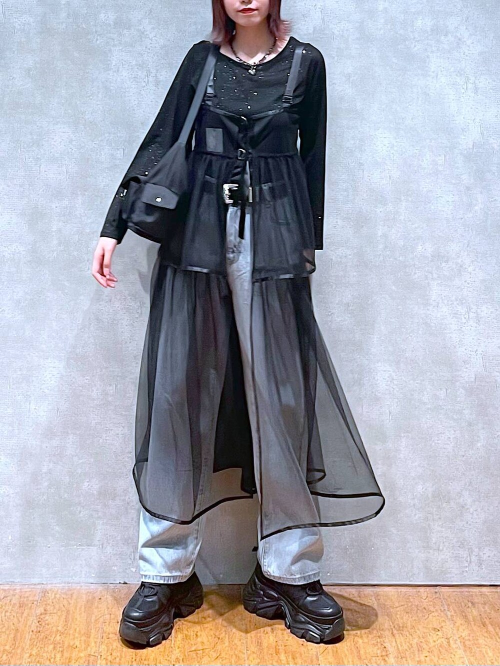 ブラック系のショルダーバッグ、ブラック系のスニーカー、ブルー系のデニムパンツを着用したレディースの春コーディネートの3枚目の写真