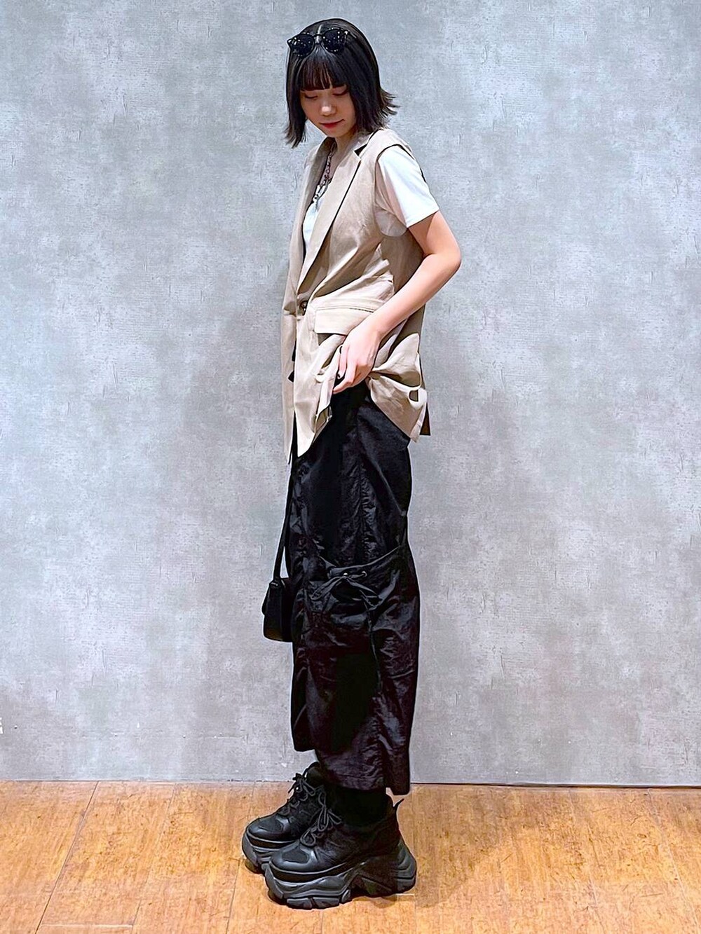 ブラック系のスニーカー、ブラック系のハンドバッグ、ホワイト系のTシャツ/カットソーを着用したレディースの夏コーディネートの3枚目の写真