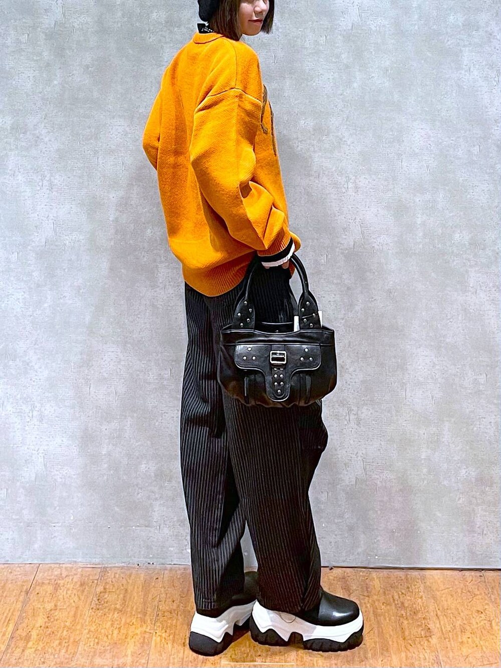 ブラック系のニット/セーター、ブラック系のデニムパンツ、ブラック系のハンドバッグを着用したレディースの秋コーディネートの6枚目の写真