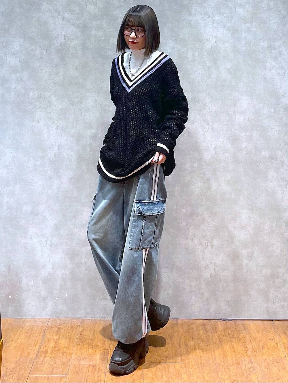 ブラック系のスニーカー、ブルー系のデニムパンツ、ブラック系のニット/セーターを着用したレディースの秋コーディネートの5枚目の写真