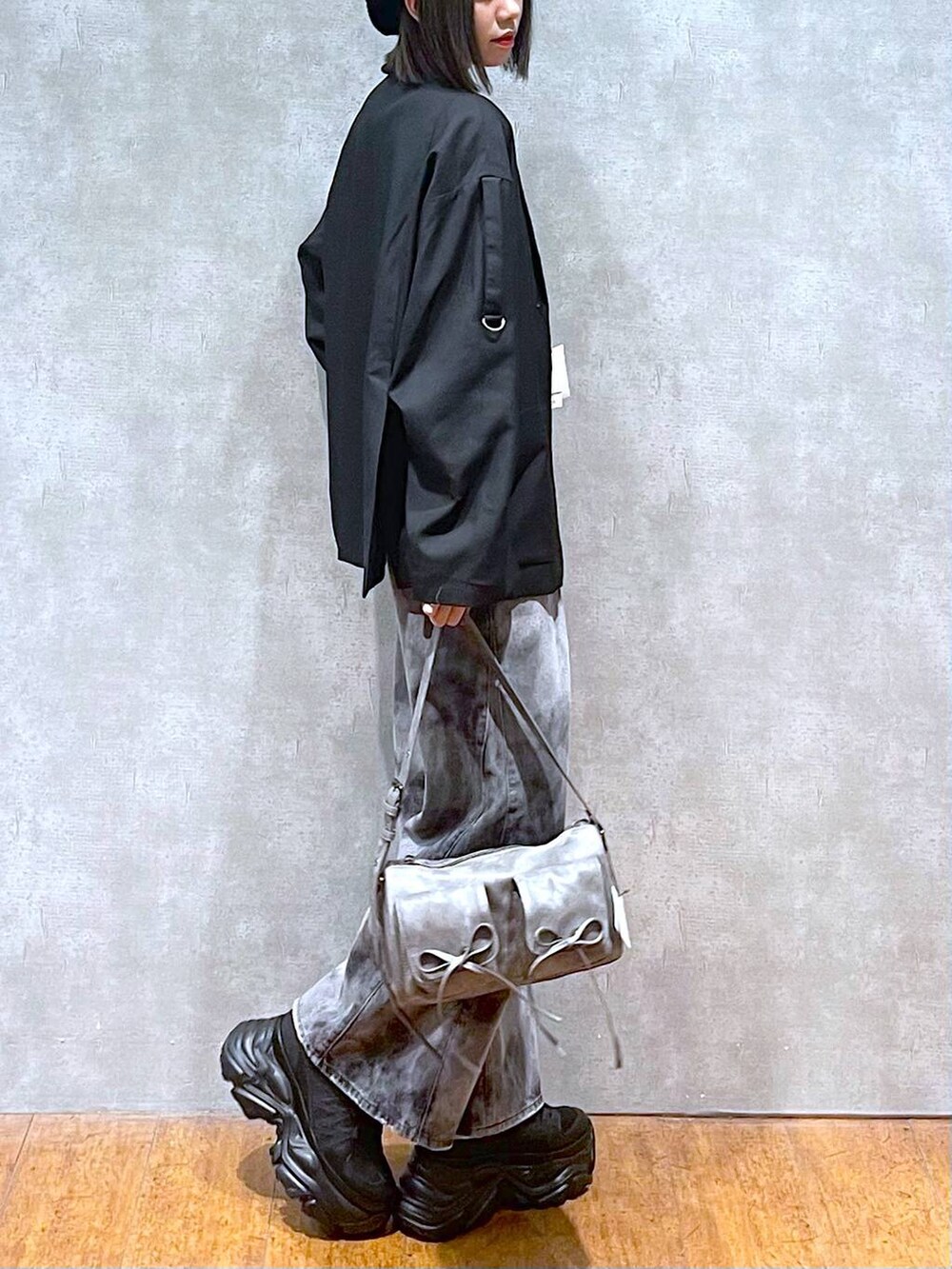 ブラック系のスニーカー、グレー系のショルダーバッグ、ブラック系のデニムパンツを着用したレディースの秋コーディネートの4枚目の写真