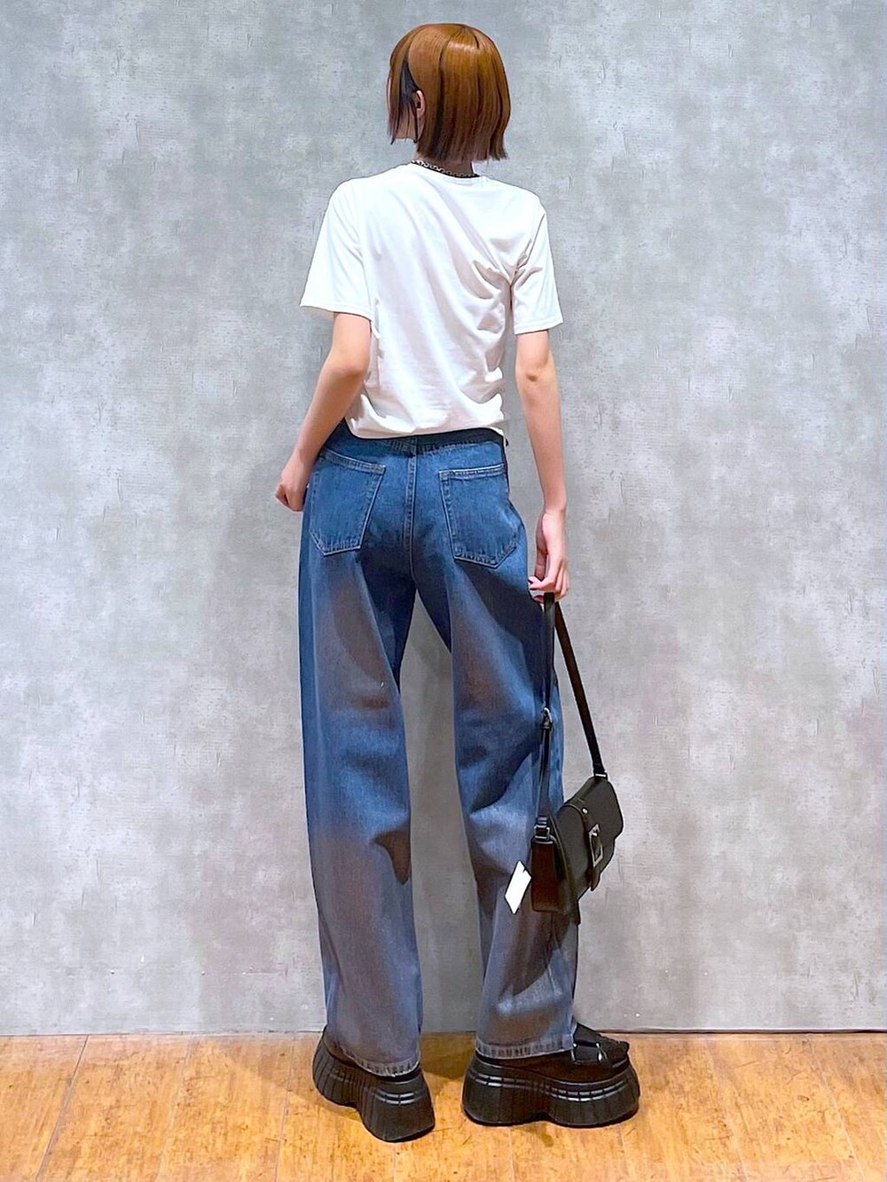 ブラック系のスニーカー、ブラック系のハンドバッグ、ホワイト系のTシャツ/カットソーを着用したレディースの夏コーディネートの6枚目の写真