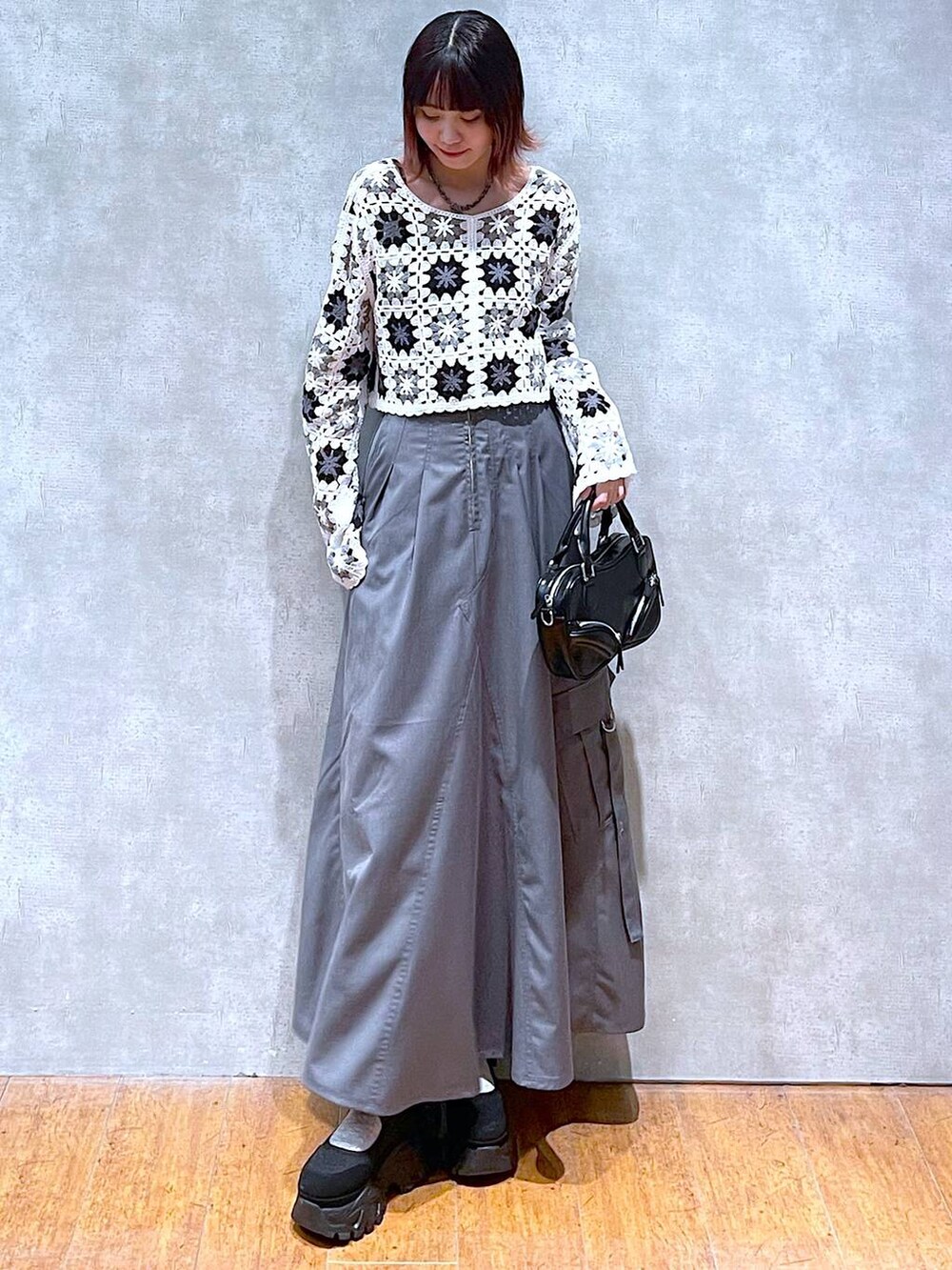 ホワイト系のカーディガン/ボレロ、ブラック系のキャミソール、グレー系のジャンパースカートを着用したレディースの春コーディネートの2枚目の写真