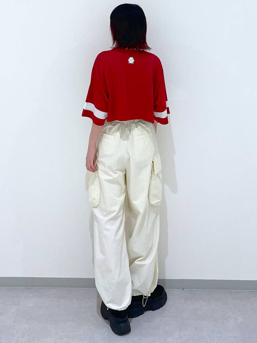 ホワイト系のカーゴパンツ、ブラック系のブーツ、レッド系のTシャツ/カットソーを着用したレディースの春コーディネートの5枚目の写真