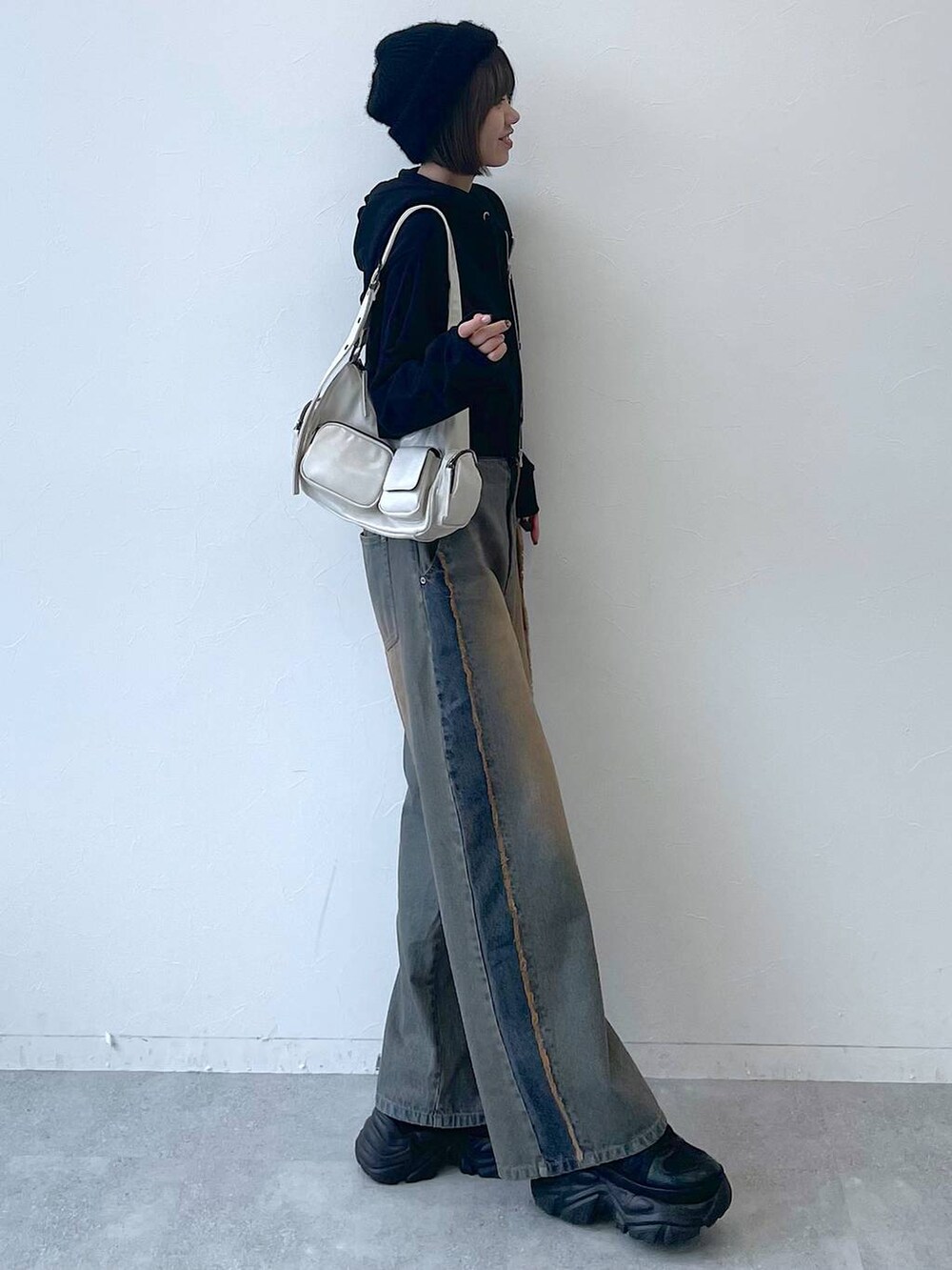 ブラック系のパーカー、ブラック系のスニーカー、ブルー系のデニムパンツを着用したレディースの秋コーディネートの2枚目の写真