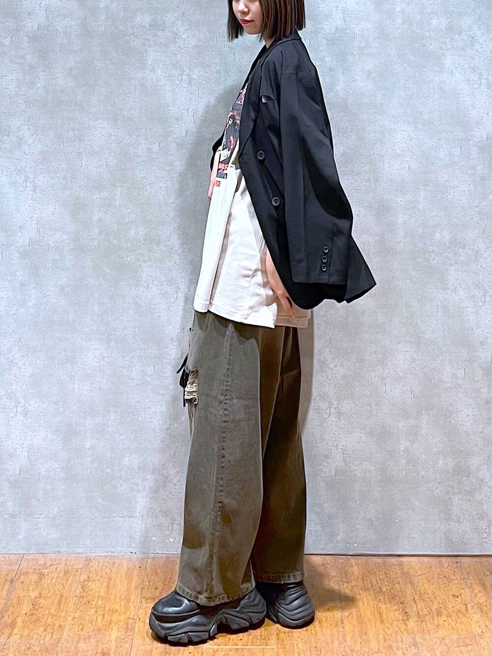 ブラック系のスニーカー、ベージュ系のTシャツ/カットソー、ブラック系のデニムパンツを着用したレディースの秋コーディネートの4枚目の写真