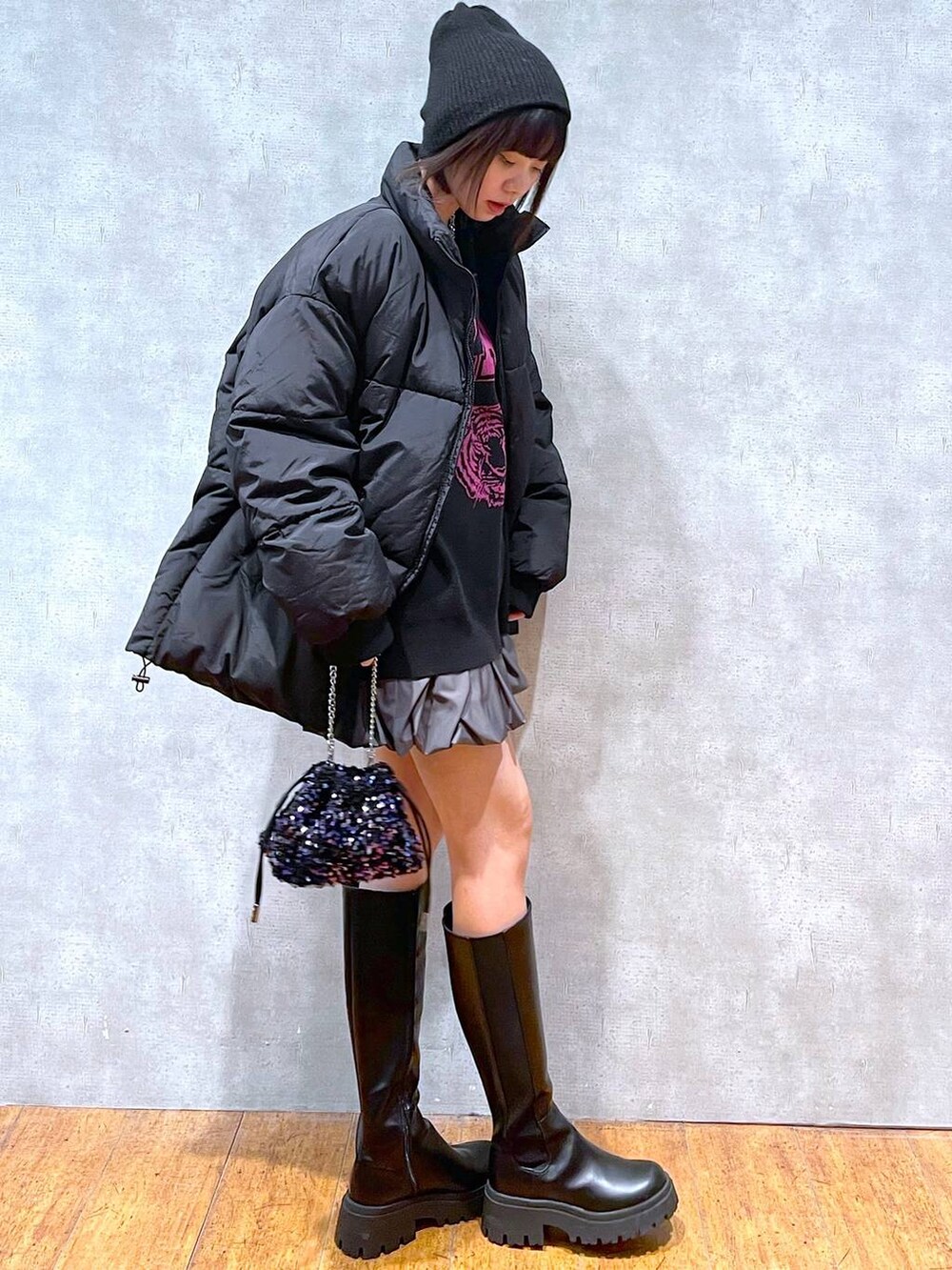 グレー系のスカート、ブラック系のブーツ、ブラック系のダウンジャケット/コートを着用したレディースの冬コーディネートの6枚目の写真