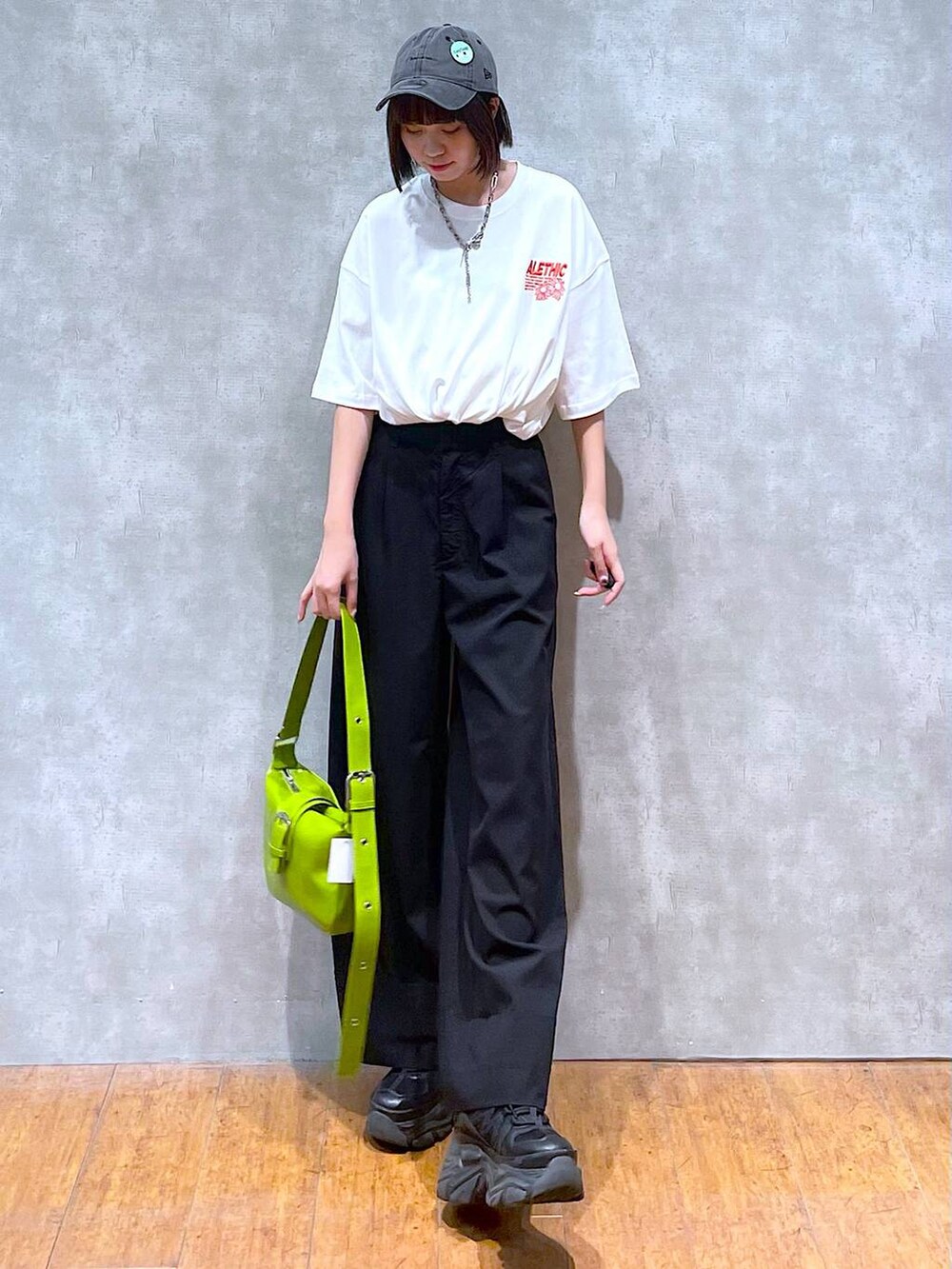 ブラック系のスニーカー、ホワイト系のTシャツ/カットソー、グリーン系のショルダーバッグを着用したレディースの夏コーディネートの3枚目の写真