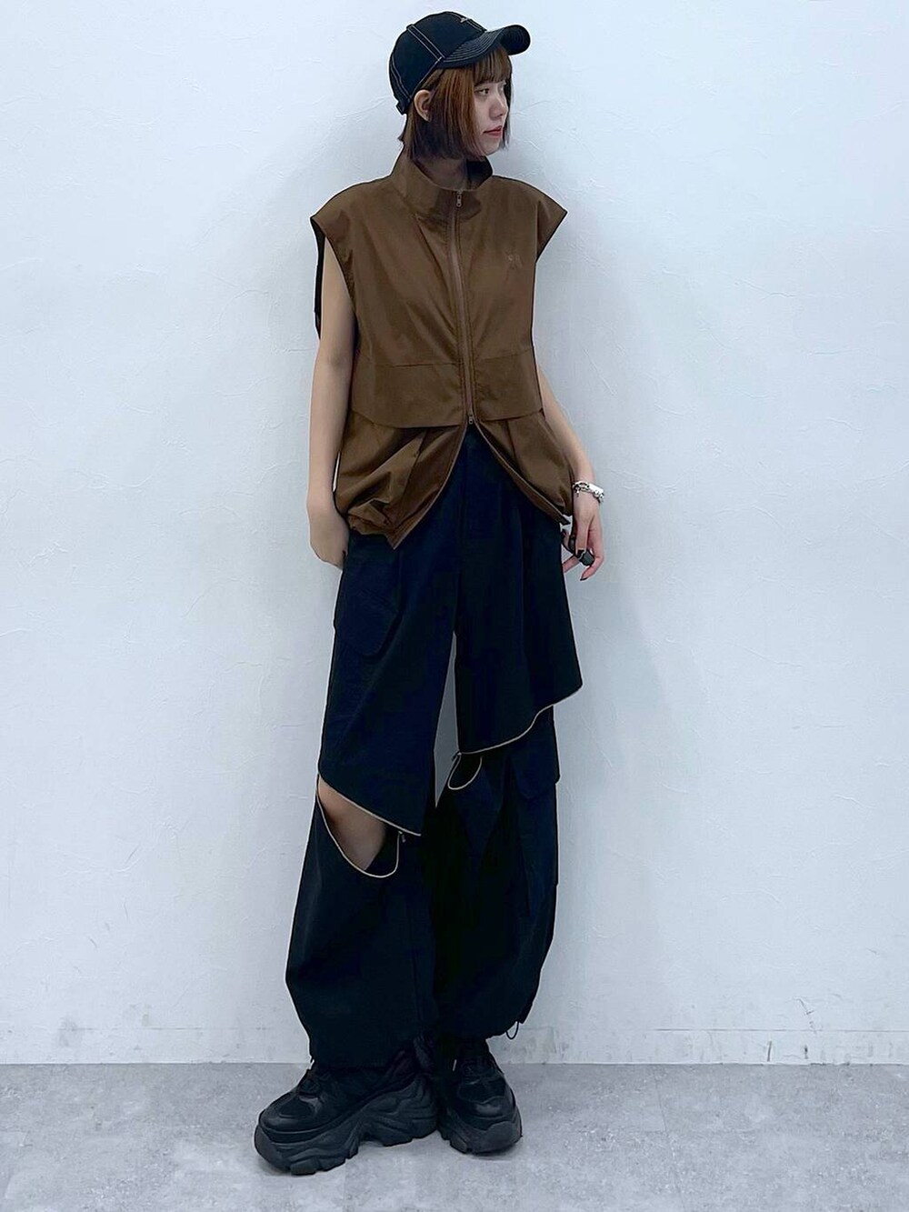 ブラック系のスニーカー、ブラック系のカーゴパンツ、ブラウン系のベストを着用したレディースの夏コーディネートの2枚目の写真