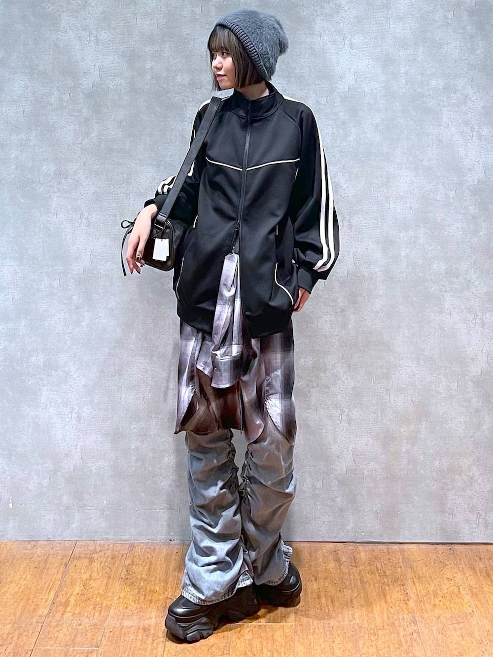 ブラック系のスニーカー、ブラック系のショルダーバッグ、ブルー系のデニムパンツを着用したレディースの秋コーディネートの7枚目の写真