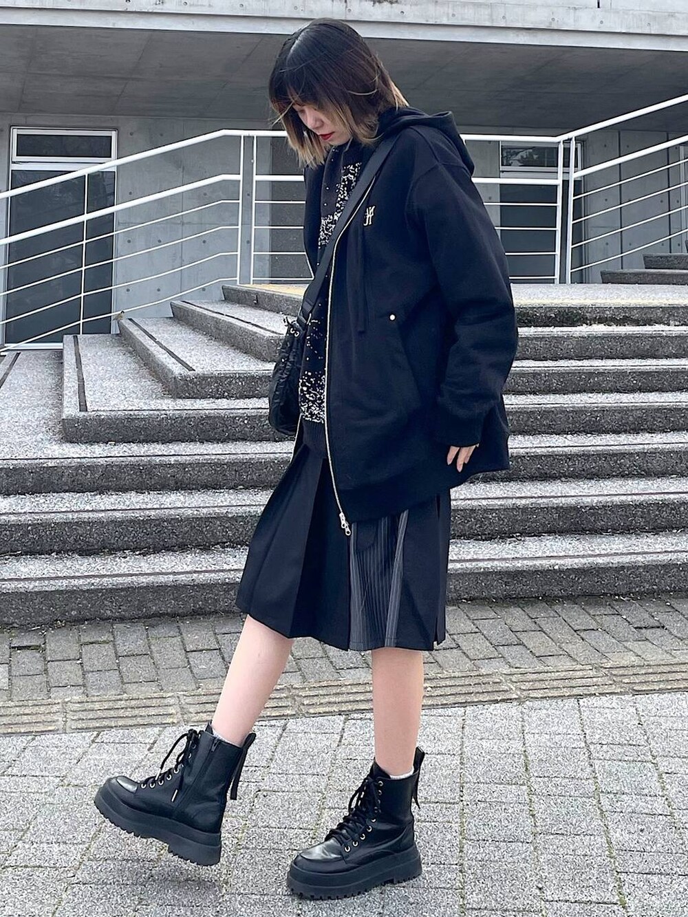 ブラック系のパーカー、ブラック系のショルダーバッグ、ブラック系のブーツを着用したレディースの冬コーディネートの6枚目の写真