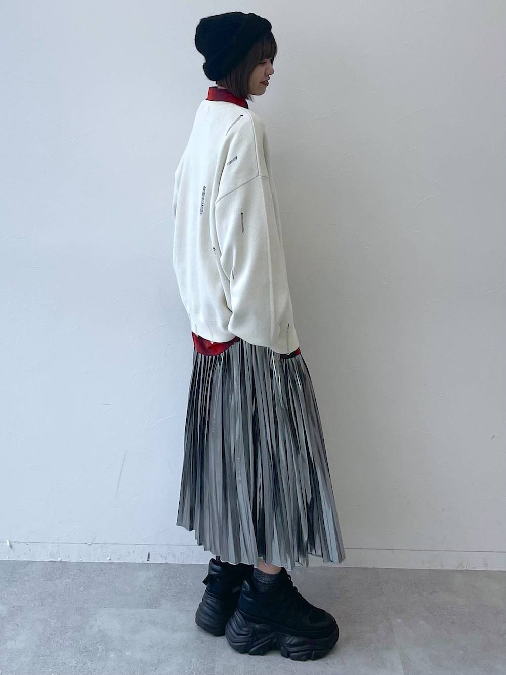 ブラック系のスニーカー、グレー系のスカート、ホワイト系のニット/セーターを着用したレディースの秋コーディネートの5枚目の写真