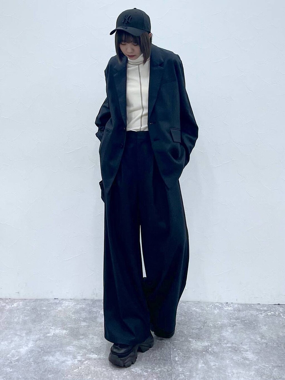 ブラック系のスニーカー、ブラック系のスラックス、ブラック系のテーラードジャケットを着用したレディースの秋コーディネートの2枚目の写真