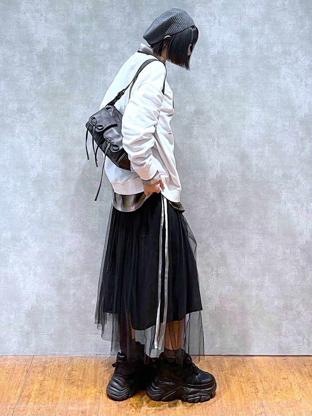 ブラック系のスニーカー、ブラック系のショルダーバッグ、ブラック系のスカートを着用したレディースの秋コーディネートの4枚目の写真