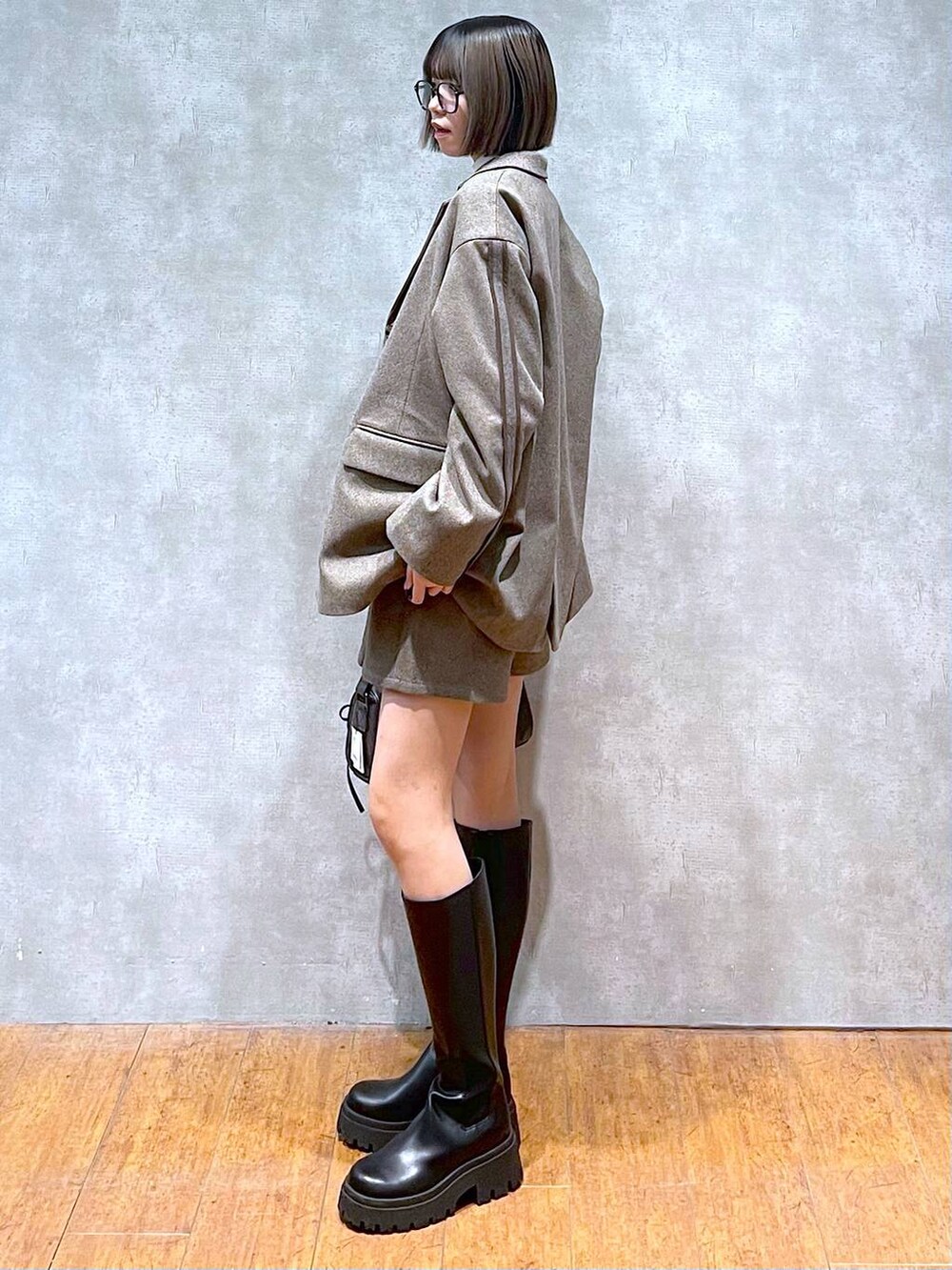 ブラック系のショルダーバッグ、ホワイト系のニット/セーター、ブラック系のブーツを着用したレディースの秋コーディネートの5枚目の写真