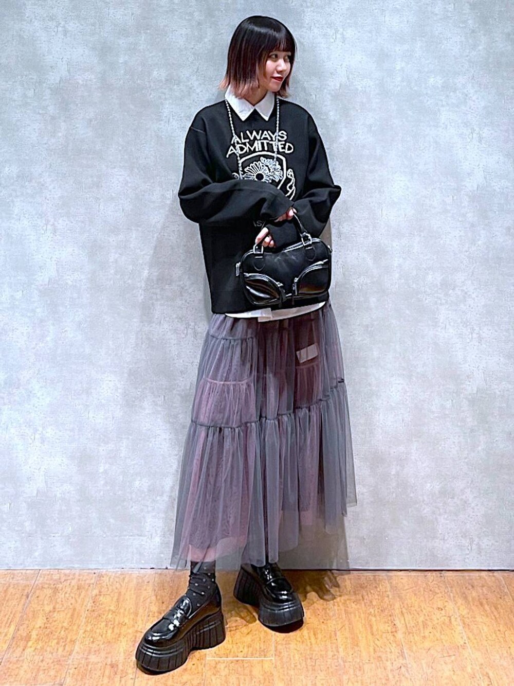 ブラック系のニット/セーター、ホワイト系のシャツ/ブラウス、グレー系のスカートを着用したレディースの春コーディネートの3枚目の写真