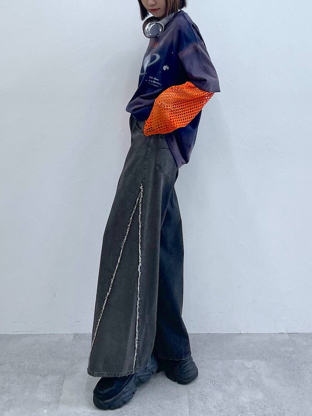 ブラック系のスニーカー、オレンジ系のTシャツ/カットソー、ブラック系のデニムパンツを着用したレディースの夏コーディネートの3枚目の写真