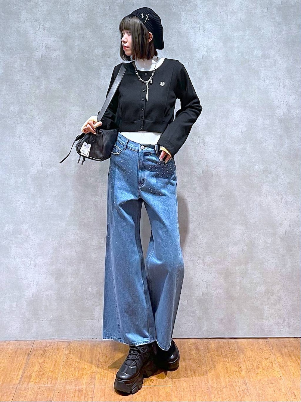 ブラック系のスニーカー、ホワイト系のニット/セーター、ブルー系のデニムパンツを着用したレディースの秋コーディネートの6枚目の写真