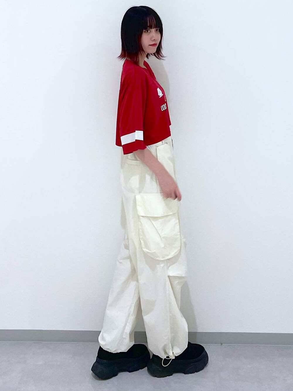 ホワイト系のカーゴパンツ、ブラック系のブーツ、レッド系のTシャツ/カットソーを着用したレディースの春コーディネートの4枚目の写真