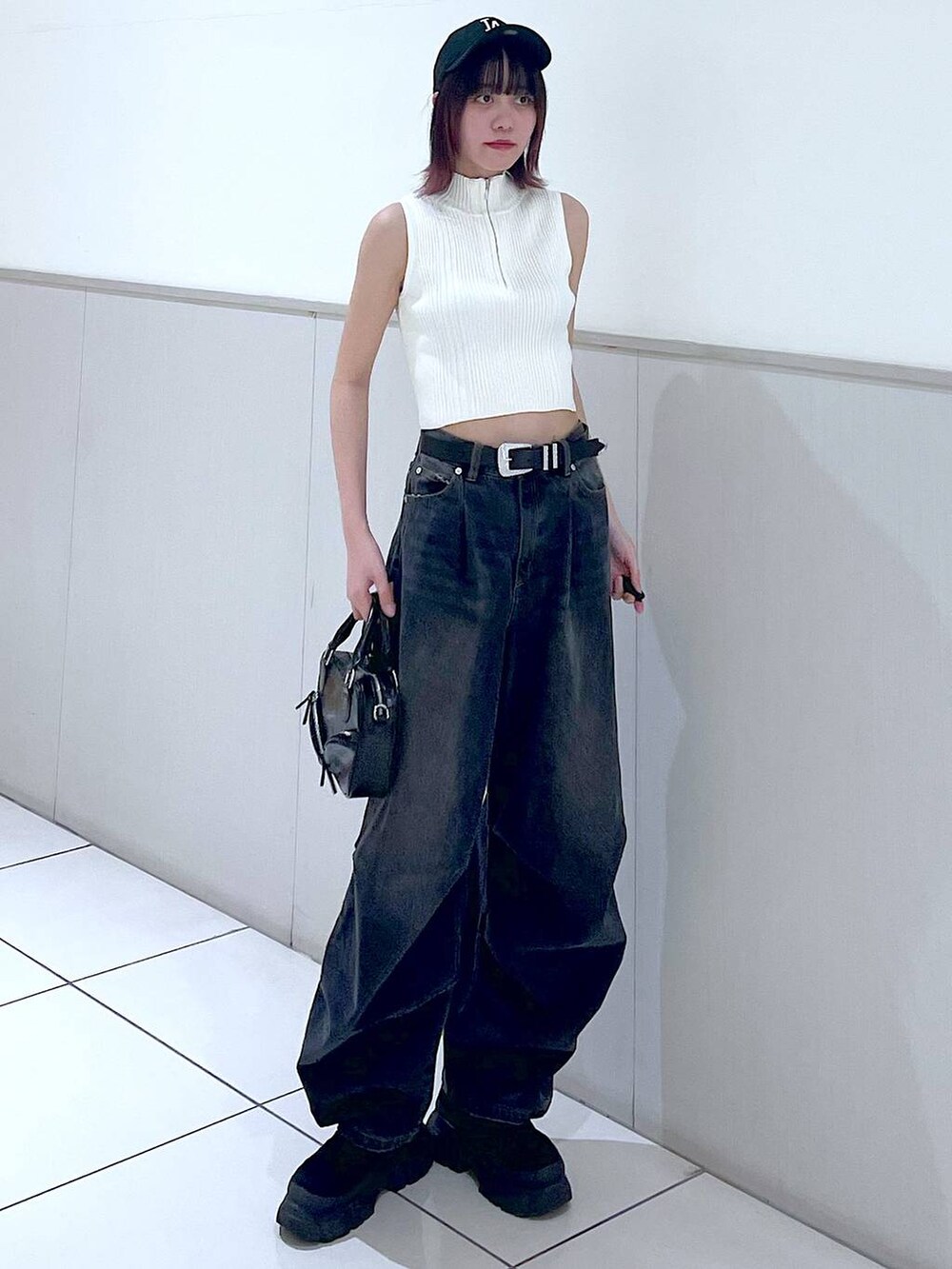 ブラック系のデニムパンツ、ホワイト系のニット/セーター、ブラック系のボストンバッグを着用したレディースの春コーディネートの3枚目の写真