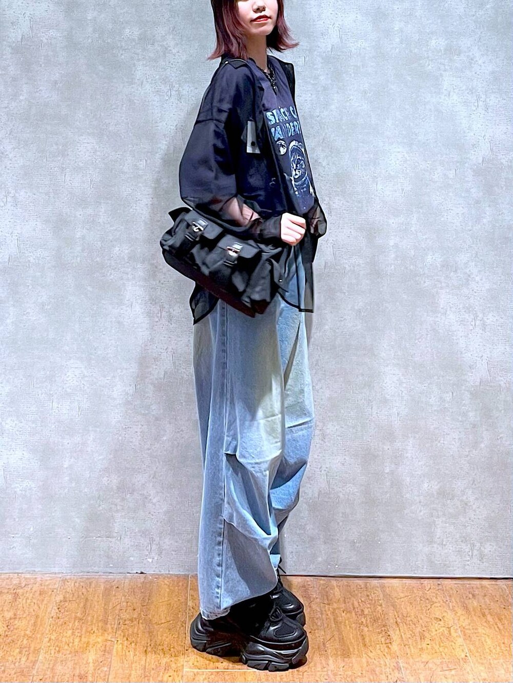 ブラック系のショルダーバッグ、ブルー系のデニムパンツ、ブラック系のスニーカーを着用したレディースの春コーディネートの5枚目の写真