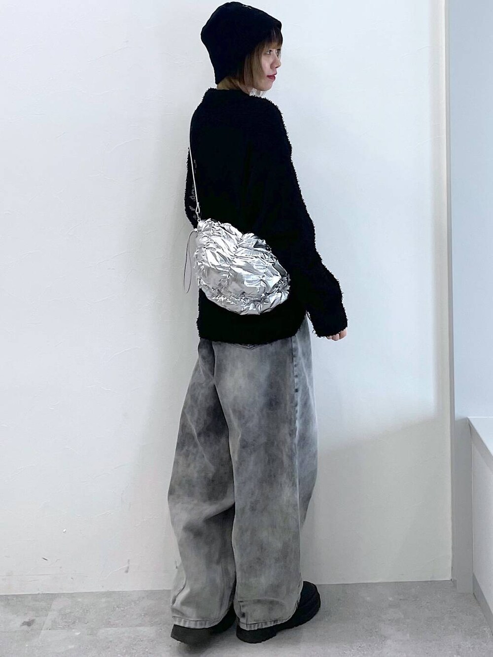 シルバー系のショルダーバッグ、ブラック系のブーツ、ブラック系のデニムパンツを着用したレディースの冬コーディネートの7枚目の写真