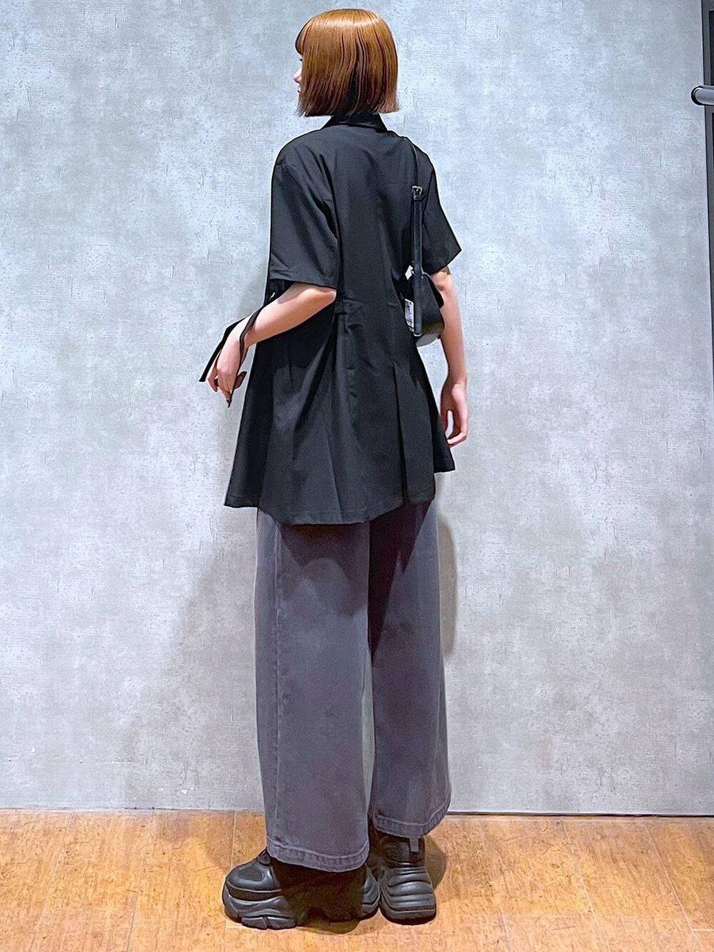 ブラック系のスニーカー、ホワイト系のTシャツ/カットソー、ブラック系のハンドバッグを着用したレディースの夏コーディネートの6枚目の写真