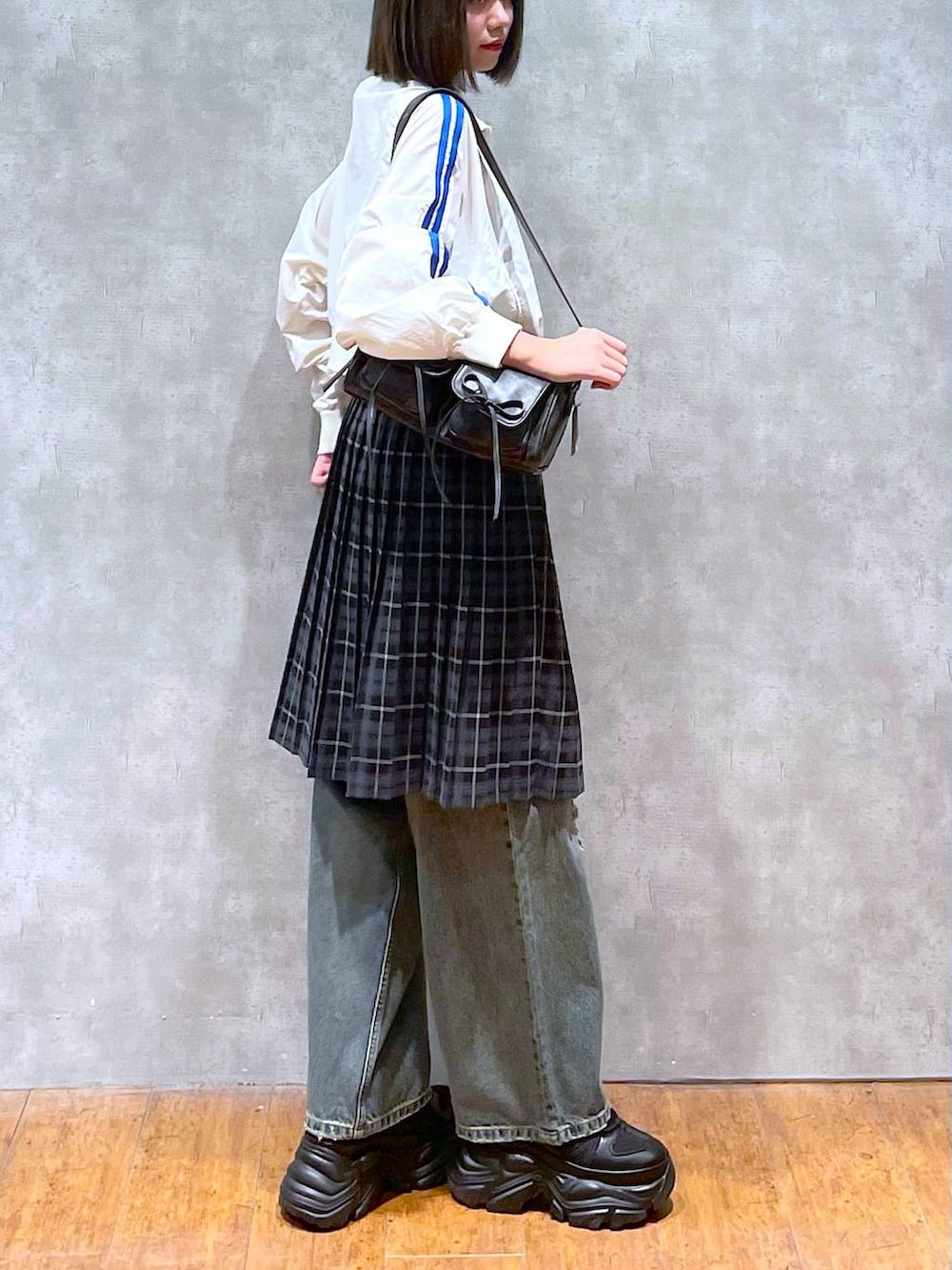 ブラック系のスニーカー、ブラック系のショルダーバッグ、ブルー系のデニムパンツを着用したレディースの秋コーディネートの7枚目の写真