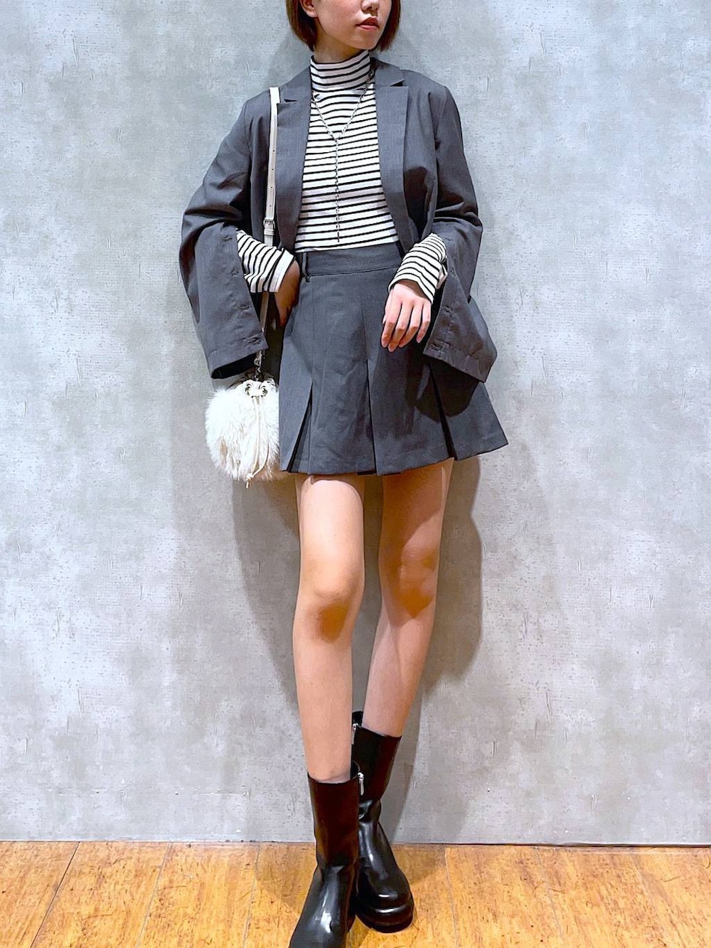 ホワイト系のショルダーバッグ、ブラック系のブーツ、グレー系のテーラードジャケットを着用したレディースの秋コーディネートの3枚目の写真