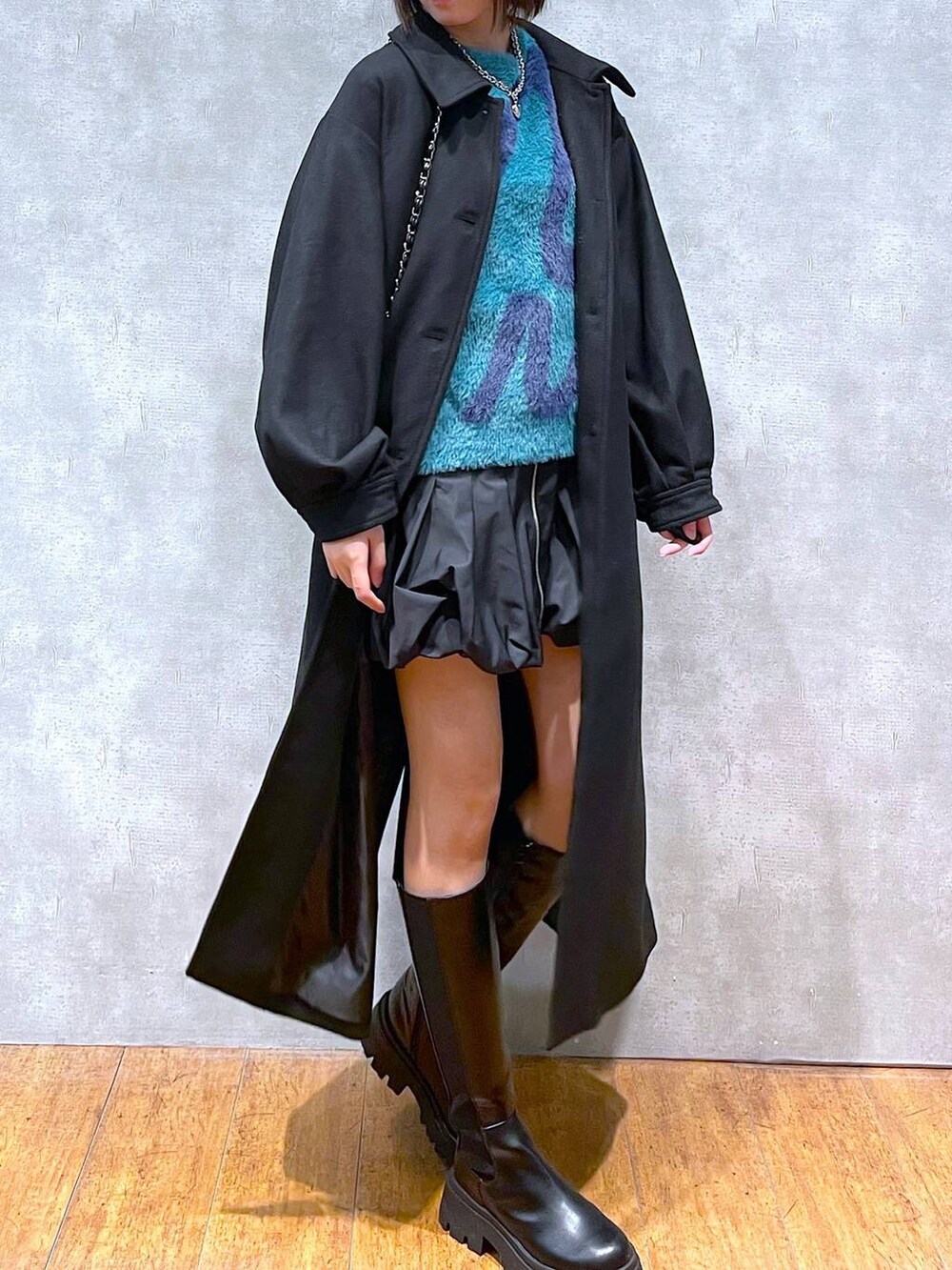 ブラック系のスカート、ブラック系のチェスターコート、ブラック系のブーツを着用したレディースの冬コーディネートの2枚目の写真