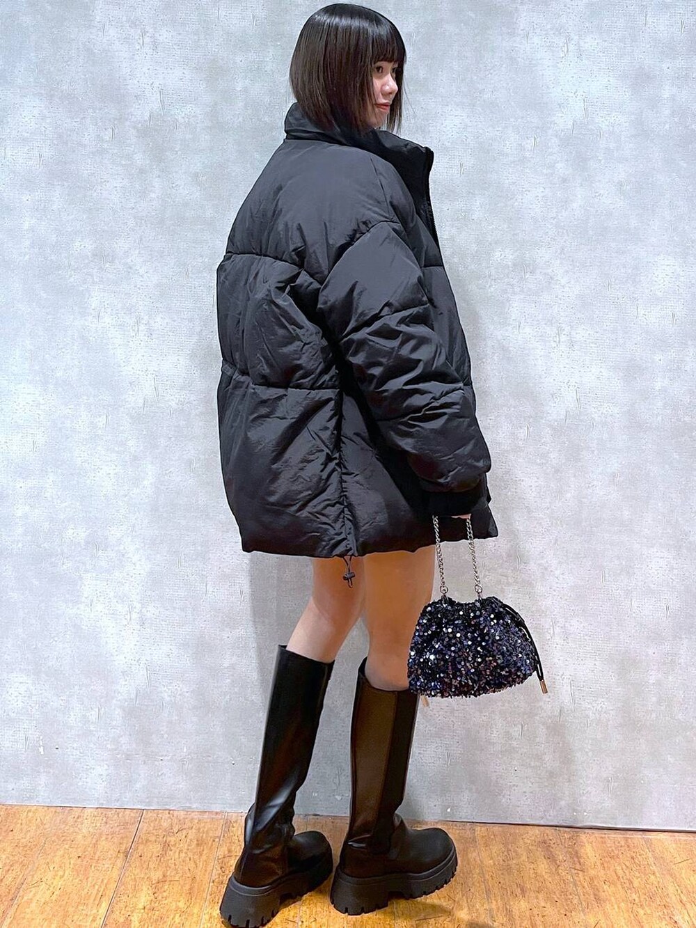 ブラック系のスカート、ブラック系のブーツ、ブラック系のダウンジャケット/コートを着用したレディースの冬コーディネートの2枚目の写真