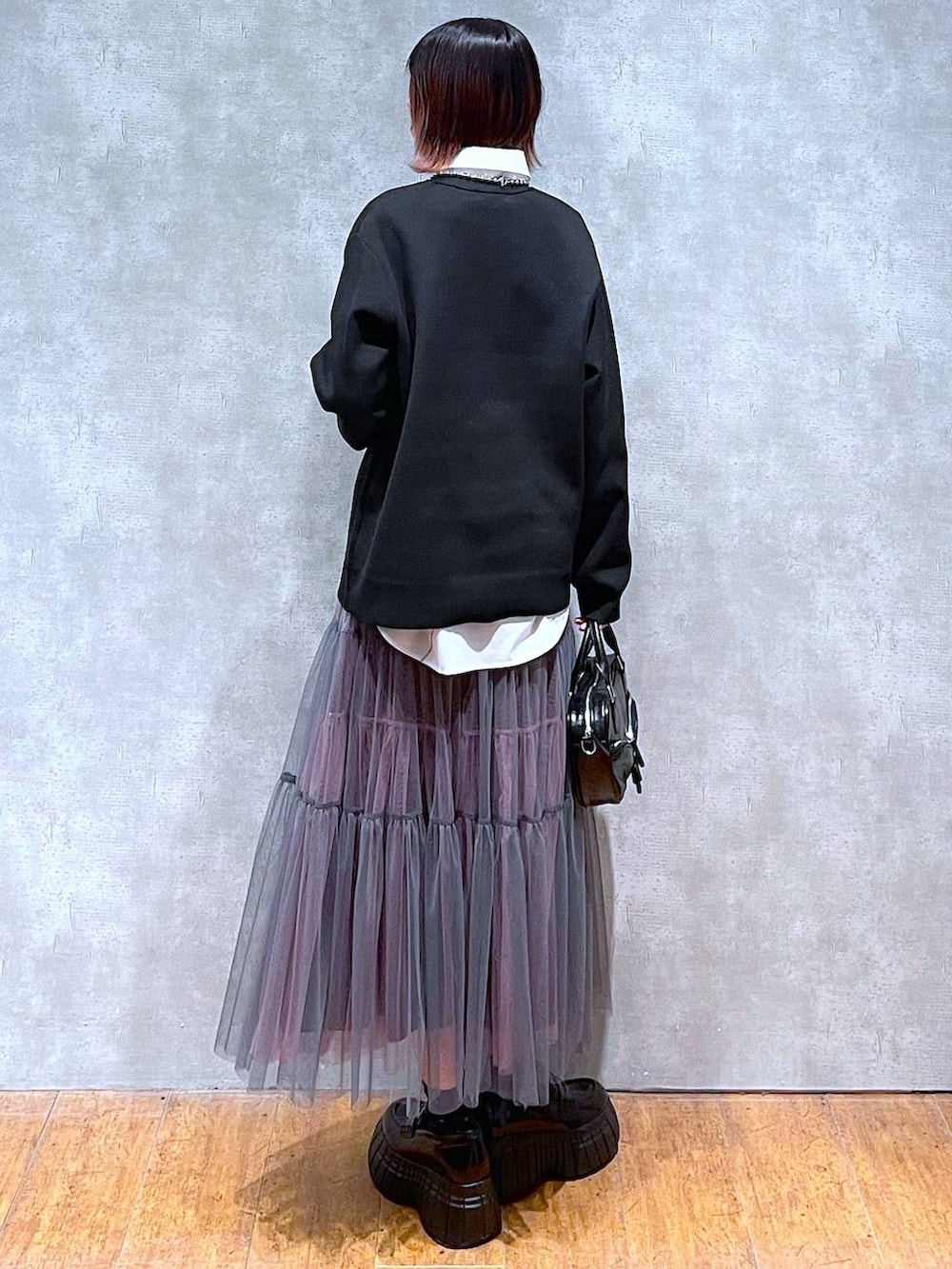 ブラック系のニット/セーター、ホワイト系のシャツ/ブラウス、グレー系のスカートを着用したレディースの春コーディネートの6枚目の写真