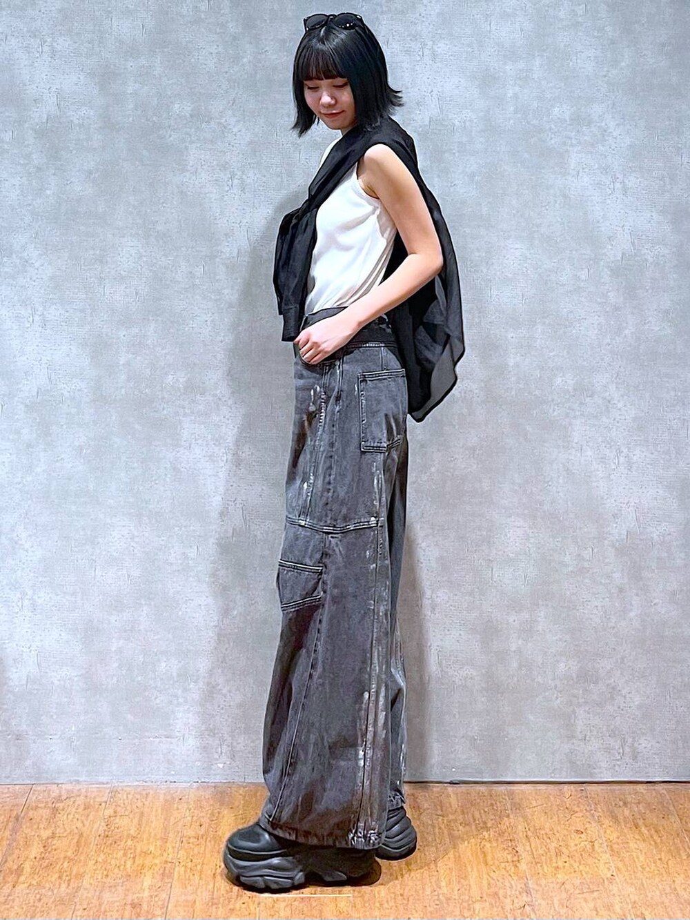 ブラック系のスニーカー、ホワイト系のタンクトップ、ブラック系のデニムパンツを着用したレディースの夏コーディネートの2枚目の写真