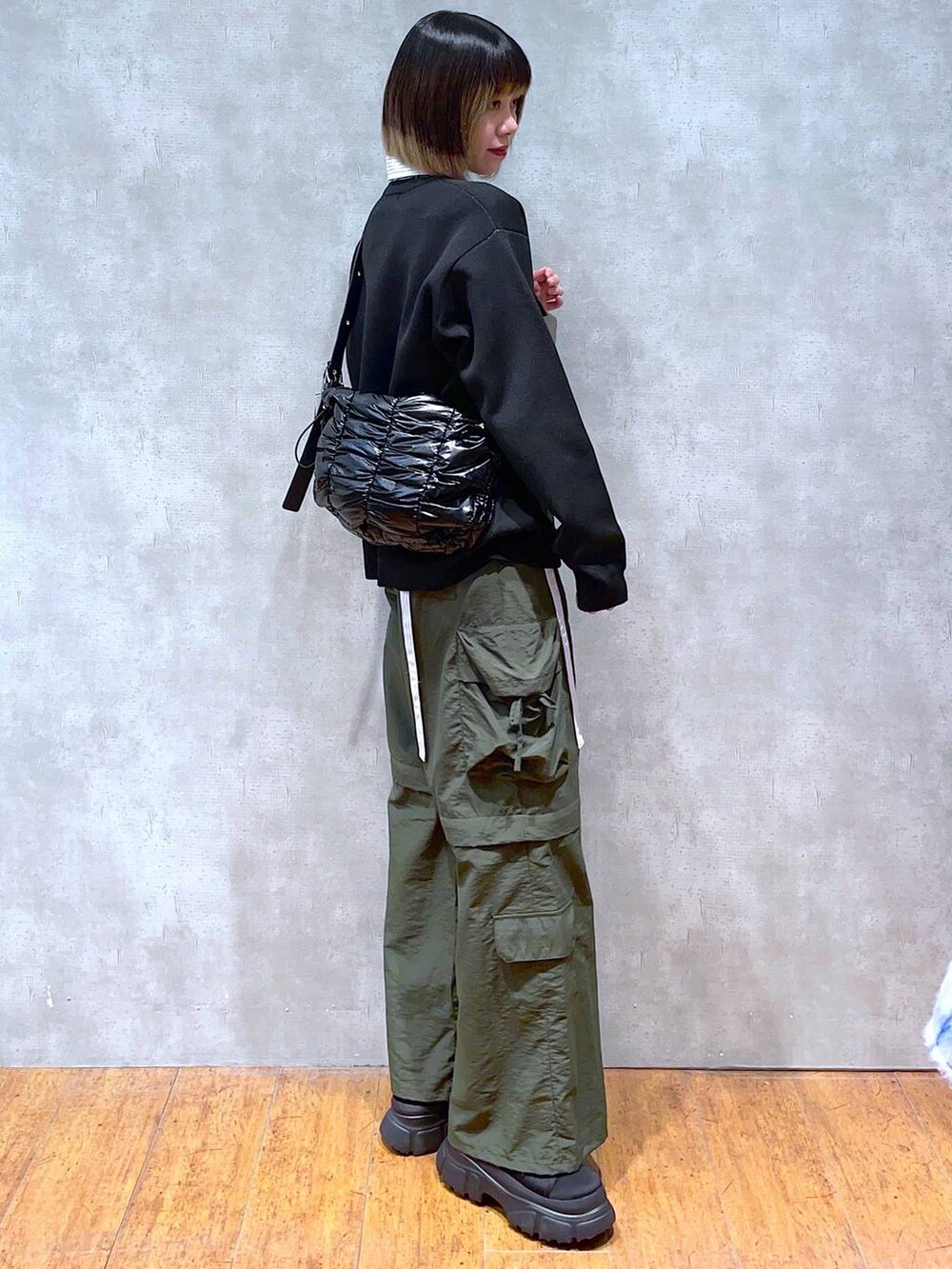 ブラック系のショルダーバッグ、ブラック系のニット/セーター、ブルー系のシャツ/ブラウスを着用したレディースの冬コーディネートの6枚目の写真