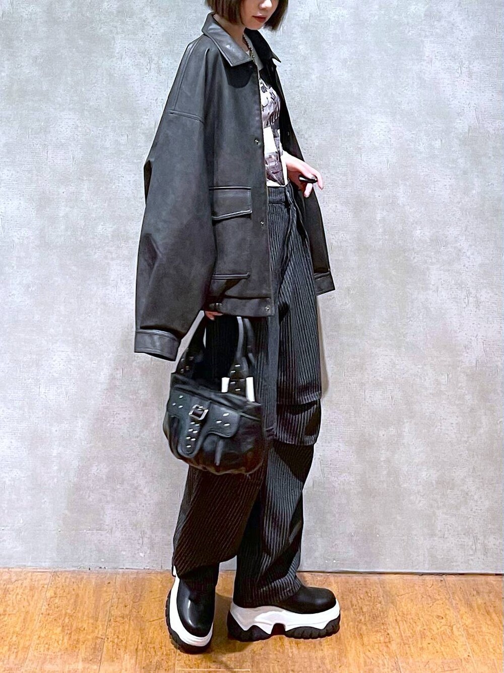 ブラック系のブルゾン、ブラック系のデニムパンツ、ブラック系のハンドバッグを着用したレディースの秋コーディネートの7枚目の写真