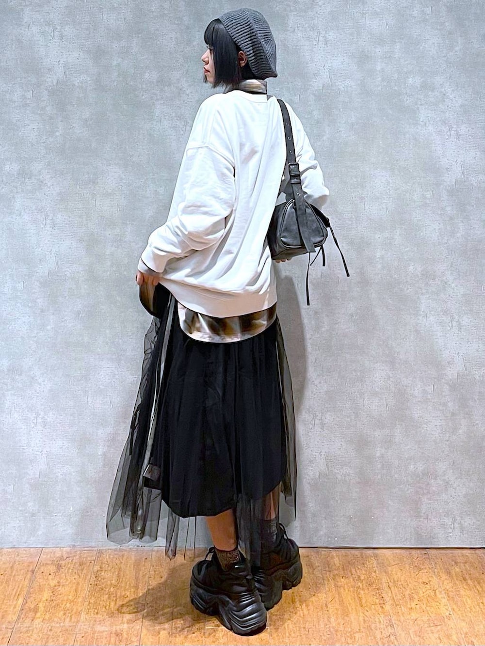 ブラック系のスニーカー、ブラック系のショルダーバッグ、ブラック系のスカートを着用したレディースの秋コーディネートの3枚目の写真