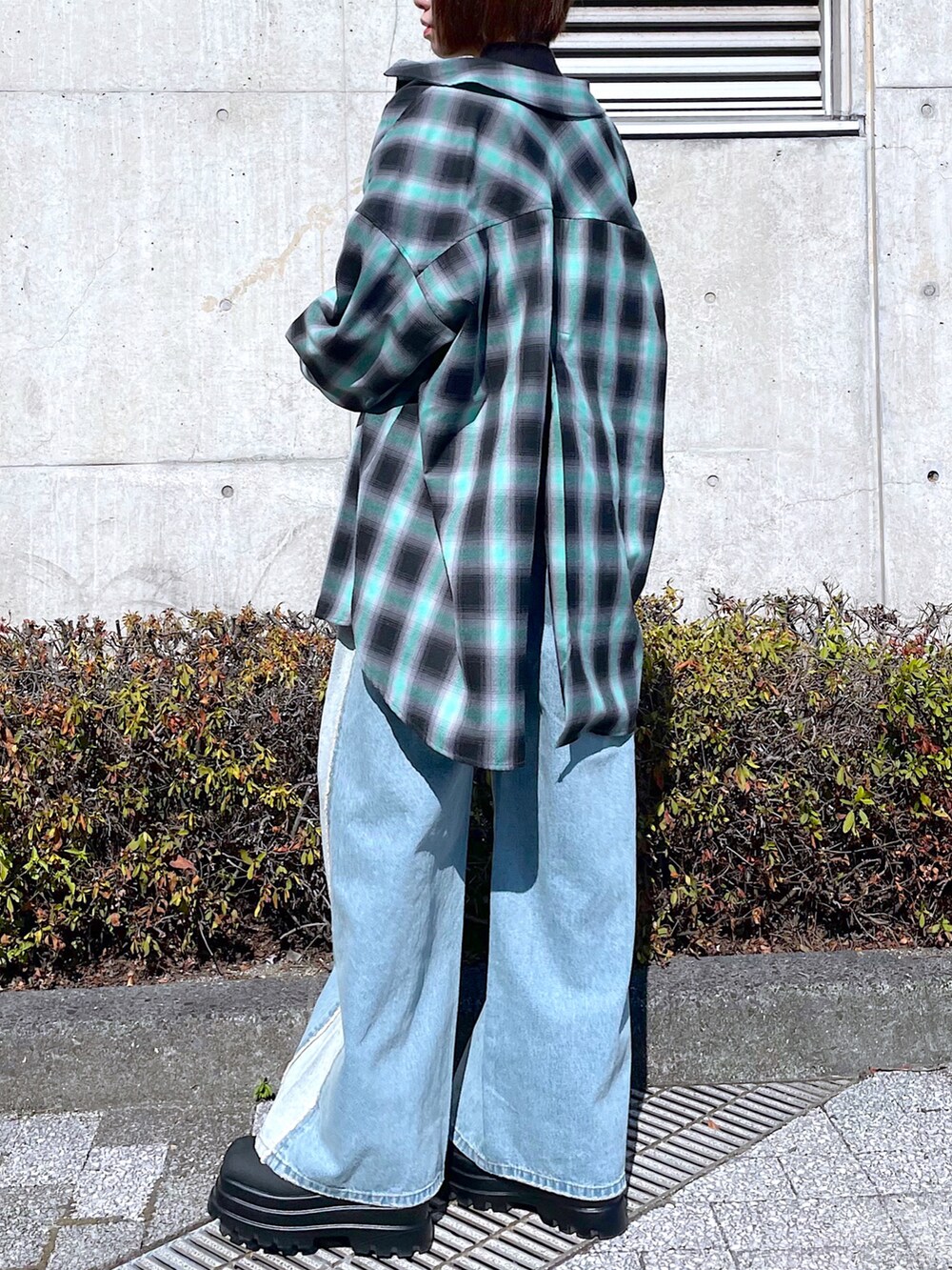 ブラック系のニット/セーター、グリーン系のシャツ/ブラウス、ブルー系のデニムパンツを着用したレディースの秋コーディネートの2枚目の写真